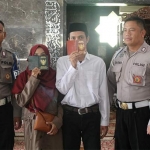 Tahanan Polresta Sidoarjo Doni Oktavianto Wibowo dan istrinya menunjukkan buku nikah.