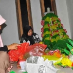 KREATIF: Milla (jilbab hitam) dibantu saudaranya sedang mengerjakan pesanan baju berbahan plastik bekas. Foto: EKY NURHADI/ BANGSAONLINE.com