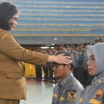 Pj Wali Kota Kediri, Zanariah, saat memakaikan topi secara simbolis kepada salah seorang anggota Satlinmas. Foto: Ist