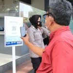 Salah satu warga yang hendak masuk ke Mapolres Tuban saat melakukan scan QR code menggunakan aplikasi PeduliLindungi.