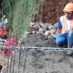 Seorang pekerja dari rekanan Dinas PU Bina Marga Kabupaten Pasuruan saat mengerjakan infrastruktur yang rusak akibat diterjang banjir dan longsor.