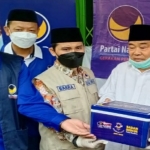 Ketua DPD Nasdem Kabupaten Mojokerto H. Suwandi secara simbolis memberikan satu boks dosis vaksin kepada Pengasuh PP Amanatul Ummah Kiai Asep, disaksikan Gus Barra. (foto: ist)