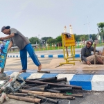 Seorang petugas menuang sampah yang berhasil di keluarkan dari gorong-gorong yang tersumbat di Alun-alun Trunojoyo. (dok. RRI)