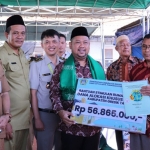 Bupati Gresik, Fandi Akhmad Yani, saat menyerahkan bantuan bedah RTLH dan sertifikat. Foto: SYUHUD/BANGSAONLINE