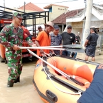 Petugas BPBD Gresik dan Bhabinkamtibmas saat menyiapkan perahu karet untuk evakuasi korban banjir luapan Kali Lamong. Foto: Ist.