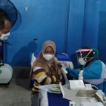 Ketua DPD Partai NasDem Kabupaten Kediri, Lutfi Mahmudiono, saat memberi semangat kepada seorang ibu yang ketakutan ketika disuntik vaksin oleh Petugas. Foto: MUJI HARJITA/ BANGSAONLINE.com