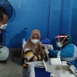 Ketua DPD Partai NasDem Kabupaten Kediri, Lutfi Mahmudiono, saat memberi semangat kepada seorang ibu yang ketakutan ketika disuntik vaksin oleh Petugas. Foto: MUJI HARJITA/ BANGSAONLINE.com