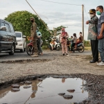 TERGENANG: Pj. Bupati Hudiyono menunjuk salah satu lubang jalan di Desa Kwangsan Sedati, Kamis (29/10) sore. foto: ist.