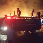 Mobil damkar beserta petugas yang tiba di TKP kebakaran saat melakukan pemadaman api