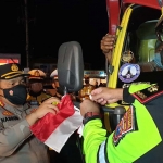 Kapolresta Banyuwangi AKBP Nasrun Pasaribu (kiri) saat mengikat bendera merah putih ke spion salah satu truk logistik.