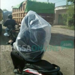 Pengendara sepeda motor membungkus badannya dengan plastik agar terhindar dari debu jalan Betoyo-Pecuk. foto: SYUHUD/ BANGSAONLINE