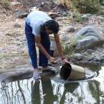 TERPAKSA: Seorang warga Desa Sambirobyong Kecamatan Berbek mengambil air sungai akibat sumur kering. foto: soewandito/BANGSAONLINE