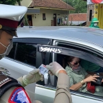 Anggota Satuan Polisi Lalu Lintas mengecek identitas pengendara saat hendak masuk ke wilayah Kabupaten Blitar.