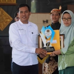 Ketua PWI Tuban, Suwandi ketika memberikan penghargaan dan hadiah kepada Naswa juara 1 lomba foto jurnalistik. Foto: Gunawan Wihandono/BANGSAONLINE.com