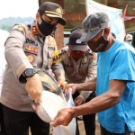 Kapolres Mojokerto AKBP Dony Alexander ikut membagikan langsung bantuan beras ke masyarakat.