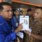 Sugiharto (kiri) memperlihatkan meme berlogo angka 1 yang viral di media sosial yang diduga disebarkan Timses pasangan calon tertentu di Pilkada Jombang. foto: Rony/ BANGSAONLINE