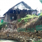 Rumah warga yang berada di dekat tebing sungai rusak akibat tergerus air saat hujan deras. foto: RONY S/ BANGSAONLINE