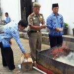 Kepala Dispendukcapil Pacitan, Supardianto bersama Kasatpol PP, Widi Sumardji saat melakukan pemusnahan KTP rusak. 