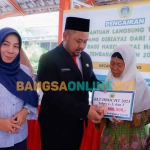 Bupati Gresik, Fandi Akhmad Yani, didampingi Ummi Khoiroh selaku kepala dinas sosial ketika menyalurkan BLT DBHCHT di Kecamatan Panceng. Foto: SYUHUD/BANGSAONLINE
