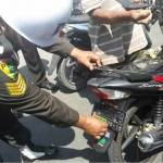 Petugas saat mencopot stiker bergambar atribut TNI dari sepeda motor milik warga. foto: dendi martoni/BANGSAONLINE