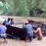 Para penambang dibantu warga berupaya mengevakuasi pikap yang terseret banjir.
