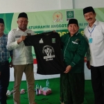 H. Syafiuddin, S.Sos. menyerahkan kaos secara simbolis kepada Ketua DPC PKB Sumnenep KH. Imam Hasyim yang disaksikan Calon Bupati Sumenep KH. Fattah Jasin.