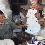 Karmiadi sedang menunjukan wayang kertas hasil tatahannya. foto: MUJI HARJITA/ BANGSAONLINE