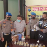 Wakapolres Pasuruan Kompol Muhammad Harris (kiri) didampingi Kasi Propam Ipda Sugihardi saat menyerahkan urineya di Halaman Gedung Panaluan Mapolres Pasuruan. foto: ANDY F/ BANGSAONLINE
