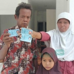Parwoto bersama istri dan anaknya menunjukkan KTP-nya. foto: NOVIAN/ BANGSAONLINE