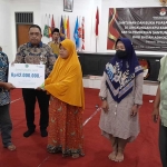 Ketua KPU Sidoarjo M Iskak menyerahkan santunan kematian kepada ahli waris petugas Pemilu 2024, Jumat (29/3/2024). foto: MUSTAIN/ BANGSAONLINE