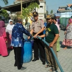 Kapolsek Duduksampeyan AKP I Made Jatinegara saat distribusi air bersih. foto: Syuhud/ bangsaonline.com