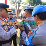 Kapolres Madiun saat menyematkan pita untuk personel yang bertugas dalam Operasi Patuh Semeru 2023. Foto: HENDRO SUHARTONO/BANGSAONLINE