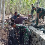 Satgas TMMD memasang bongkahan batu kali untuk pembangunan irigasi.