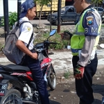 Seorang pelajar sekolah SMP sedang ditilang petugas karena kedapatan tidak memakai helm dan masih di bawah umur.