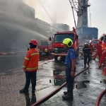 Petugas Damkar saat melakukan pembasahan area kebakaran Kapal peti kemas Verizon