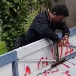 Salah satu warga saat hendak membongkar spanduk terkait keberadaan makam dadakan di kawasan Perumahan Istana Mentari, Kelurahan Cemengkalang, Sidoarjo.