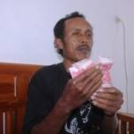 Amik Anwar ketika menunjukkan uang sogokkan dari oknum perangkat desa, agar tutup mulut. (Suwandi/BANGSAONLINE)