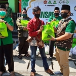 SIMBOLIS: Ketua GP Ansor Sidoarjo Riza Ali Faizin menyerahkan sembako kepada profesi terdampak Covid-19, Minggu (17/5). foto: MUSTAIN/ BANGSAONLINE