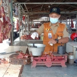 Petugas saat mengecek timbangan milik penjual daging di Pasar Setonobetek, Kota Kediri. Foto: Ist