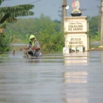 Salah satu warga Kalisari, Kecamatan Baureno nekat menyebrangi jalan yang tergenang setinggi 70 centimeter. foto: EKY NURHADI/ BANGSAONLINE