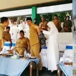 Zaenab Zuraibah saat membukakan jaket kulit suaminya (Bupati Bangkalan, R. Abdul Latif Imron) di Alun-alun Bangkalan ketika menghadiri Simulasi Manasik Haji TK-PAUD, Senin (29/07/2019). Inset: Foto Bupati Bangkalan yang melangsungkan pernikahan (kanan atas), dan surat pernyataan bersedia dimadu (bawah) yang beredar di medsos. foto: FAUZI/ BANGSAONLINE