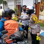 Kasatlantas Polres Batu, AKP Indah Citra Fitriani, saat memberikan buah apel kepada pengendara yang tertib berlalu lintas.