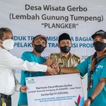 MSB Asset Properti, Komunikasi & Umum PLN UIT JBM, Tonas Hadiwidjaya menyerahkan bantuan kepada pemrakarsa program pengelolaan Desa Wisata Edukasi Gerbo, Pemuda Langganan Keramaian (Planker), disaksikan langsung oleh Kepala Desa Gerbo, Sutrisno pada Senin (27/9).