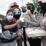 Jajaran kepolisian dari Polres Mojokerto Kota tengah membagikan masker di Jalur Perbatasan Mojokerto-Lamongan. foto: YUDI EP/ BANGSAONLINE