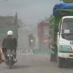 Debu jalan Betoyo-Pecuk Manyar yang berwarna hitam pekat sangat mengganggu pengguna jalan. foto: SYUHUD/ BANGSAONLINE