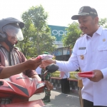 Bupati Ngawi Ony Anwar Harsono saat membagikan bendera pada warga yang melintasi Perempatan Kartonyono.