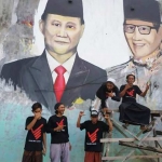 Sekelompok seniman dan relawan milenial menunjukkan hasil lukisan Prabowo-Sandi di dinding rumah warga.