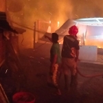 Petugas damkar saat berupaya memadamkan api yang membakar bangunan asrama.