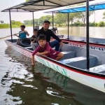 Kades Gredek, M Bahrul Ghofar menaiki perahu wisata di waduk desa. FOTO: SYUHUD/BANGSAONLINE.com