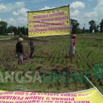 Warga memasang tulisan penolakan pembangunan SMP Negeri 3. foto: AKINA/ BANGSAONLINE